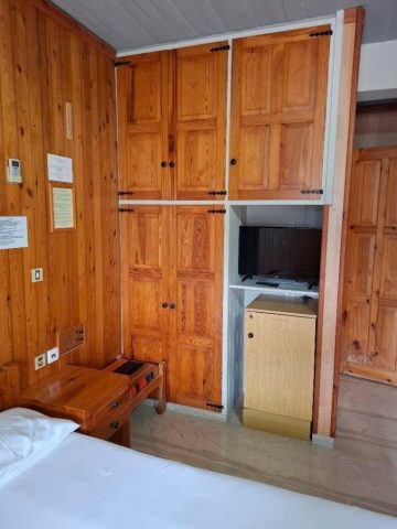 Room 1 Εσωτερικό του Δωματίου 1 στο EVDOXIA Hotel με ξύλινη ντουλάπα, τηλεόραση, μικρό ψυγείο, ξύλινες επενδύσεις και μέρος του διπλού κρεβατιού.